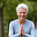 Ana, una mujer sonriente de unos 50 años, practicando yoga al aire libre